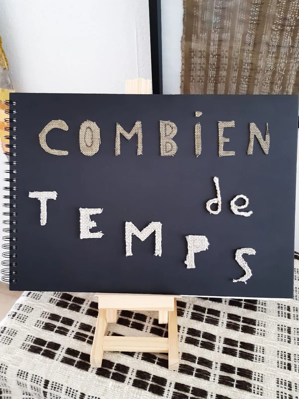 Un livret noit avec écrit 'combien de temps' de manière artistique en lettres colées